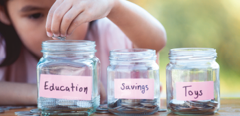 girl putting coins into money savings jars