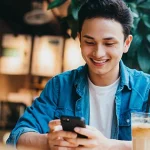 Young Asian man sitting in a cafe and on his phone