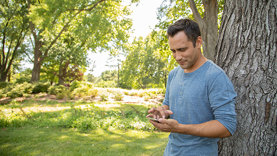 Man standing by a tree on his smartphone
