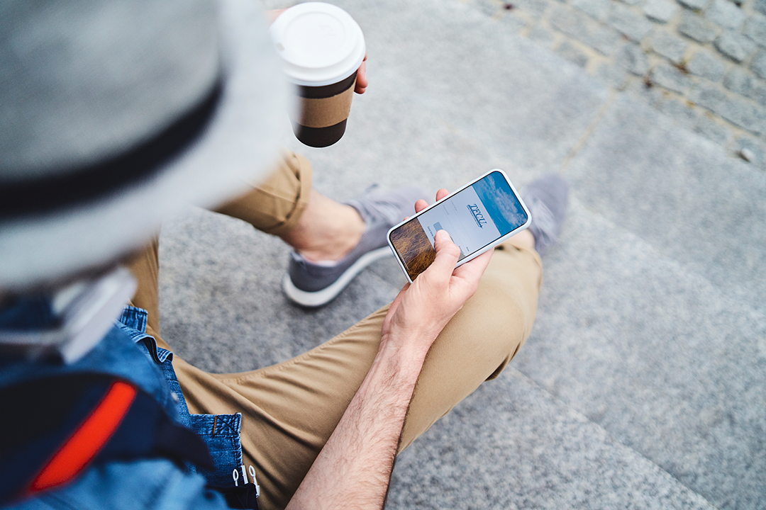 Close up of someone holding a coffee cup and a mobile device