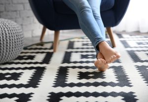 Woman sitting in a chair with feet on a black and white patterned rug.