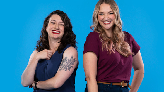 blonde and brunette employees standing smiling with blue background