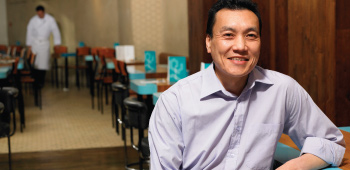 Chinese restaurant owner smiling in his dining room