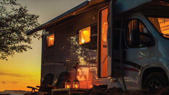 An RV reflects the sunset at a camping spot.