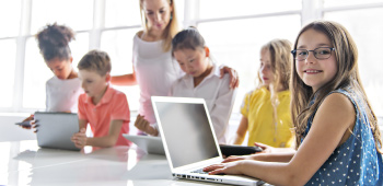 Young children using laptops and tablets supervised by adult