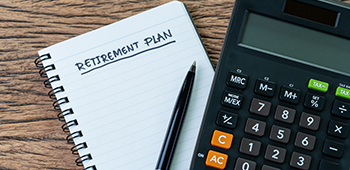 Retirement planning on a notebook with a pen and calculator