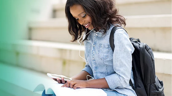 Young female student sitting on steps and looking at papers