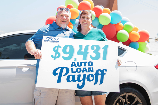 Older couple holding a great auto loan payoff winner sign