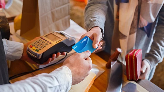 Close up of TFCU member paying at grocery store with their MoneyPlus card.