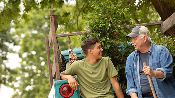 Teen and older man sitting on truck with trees