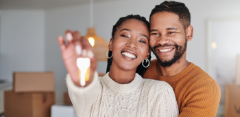 young couple smiling together and holding up keys to new house