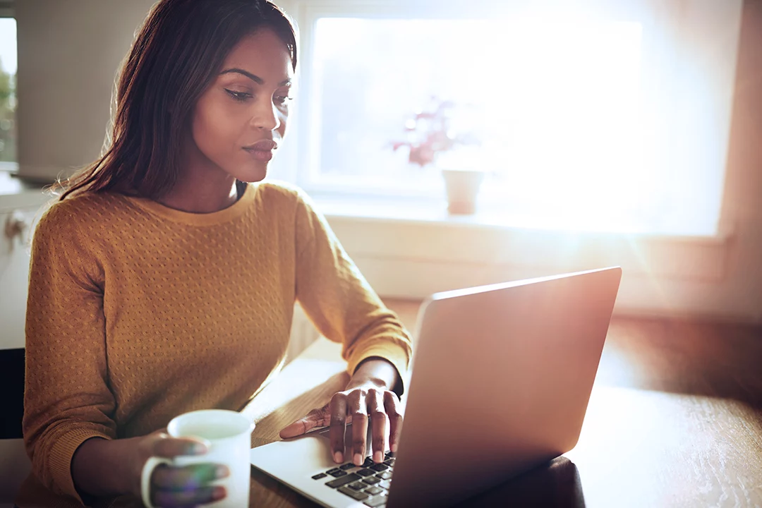 Young woman on her laptop with a mug